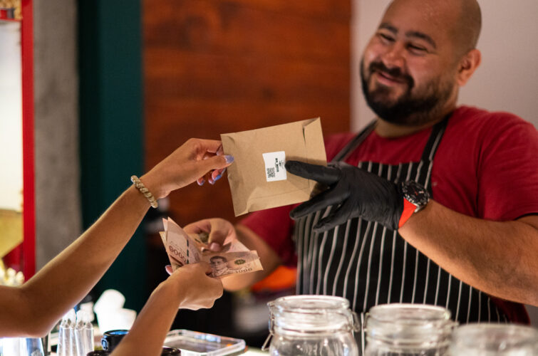 Wish, the owner of MR.WEED, smiling as he hands a customer their order
